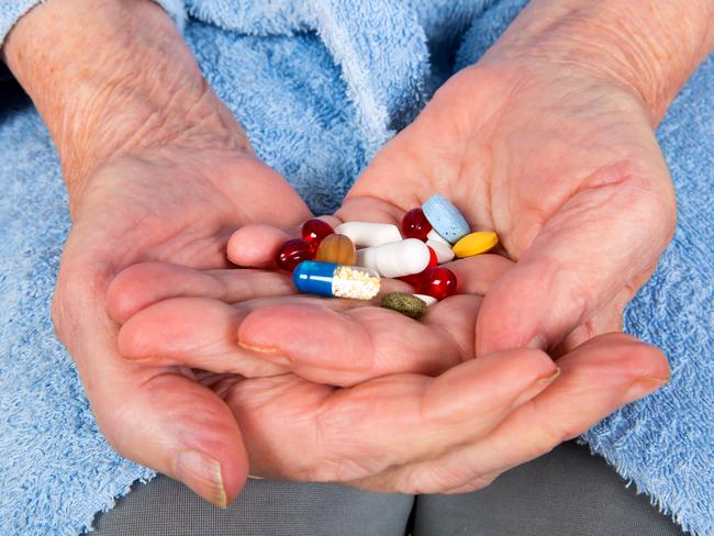 Photo of a senior patient hand holding colorful pills