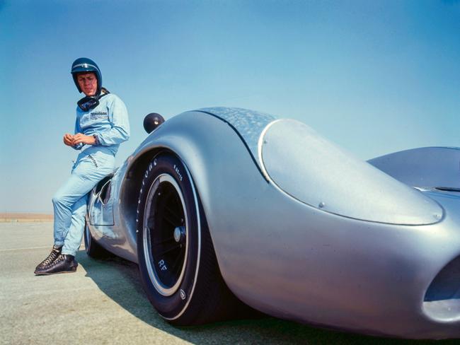 EMBARGO FOR WISH 01 AUGUST 2024. FEE MAY APPLY.American actor Steve McQueen (1930 - 1980), in Firestone racing suit, leans against a Lola T70 SL70/14 car (number 9) at Riverside Raceway, Riverside, California, July 1966. (Photo by Screen Archives/Getty Images)