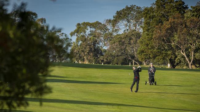 Tasmania Golf Club member Phil Fuglsang hits his second shot on the 10th hole while being watched by playing partner David Boon (right). Picture: LUKE BOWDEN