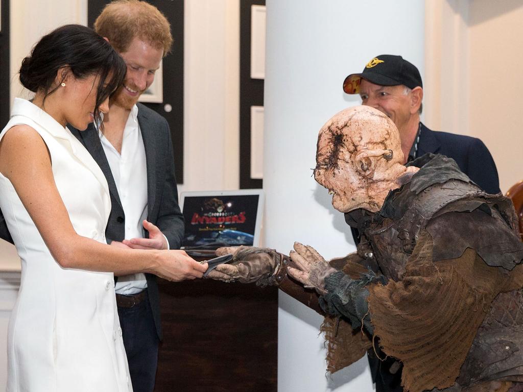 Britain's Prince Harry (2nd L) and his wife Meghan, Duchess of Sussex (L) are presented with a gift from a performer dressed as an Orc during a visit to Courtney Creative in Wellington.  Picture:  AFP