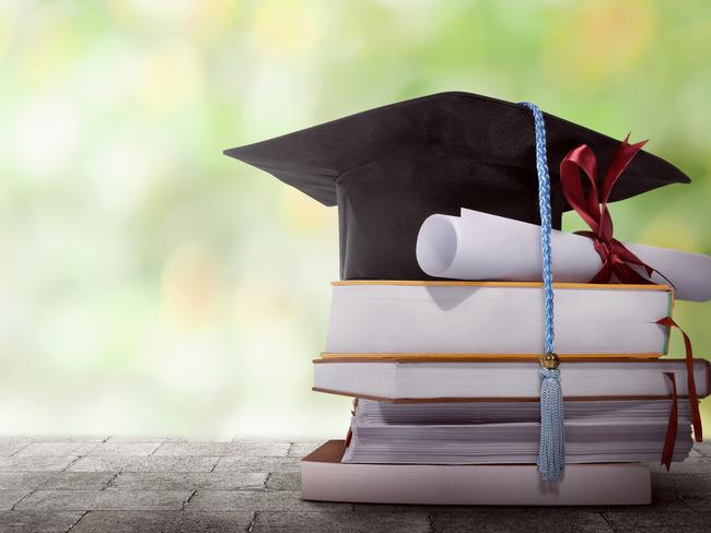 Graduation hat with degree paper on a stack of book against blurred background