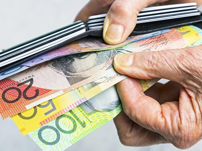 Close-up, senior female hands taking Australian banknotes (cash, currency) from purse containing many credit cards.  Horizontal, studio, copy space. . Picture: iStock