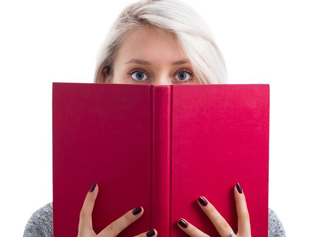 Portrait of a pretty young girl hiding behind an open red book and looking scared to camera isolated over white background.