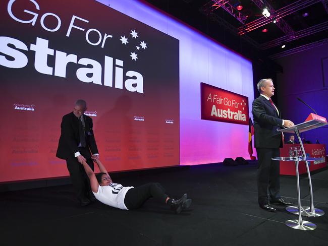 An 'Anti-Adani' protester is being removed from stage as Australian Opposition leader Bill Shorten speaks during day one of the Labor Party National Conference in Adelaide, Sunday, December 16, 2018. Labor's 48th National Conference will be held from December 16-18, 2018 at the Adelaide Convention Centre. (AAP Image/Lukas Coch) NO ARCHIVING