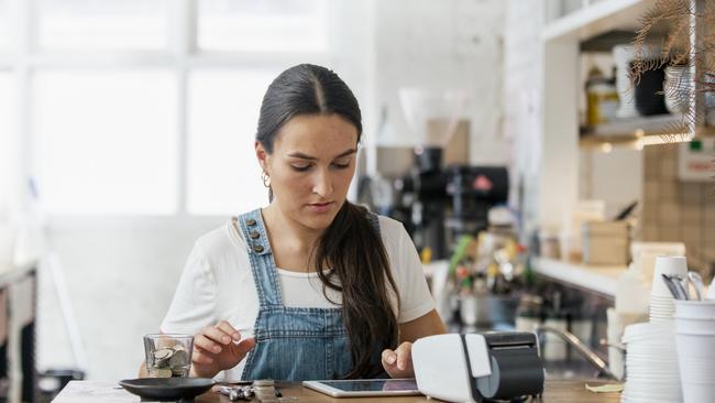 A front view shot of a waitress handling money behind a counter in a cafe.