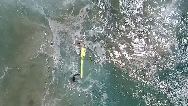 The surfers use the device to get back to shore as the drone watches on.