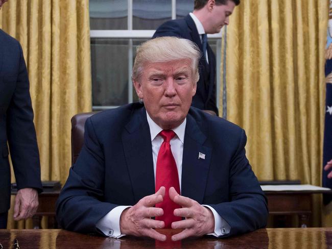 US President Donald Trump (C) waits at his desk before signing confirmations for James Mattis as US Secretary of Defense and John Kelly as US Secretary of Homeland Security, as Vice President Mike Pence (L) and White House Chief of Staff Reince Priebus (R) look on, in the Oval Office of the White House in Washington, DC, January 20, 2017. / AFP PHOTO / JIM WATSON