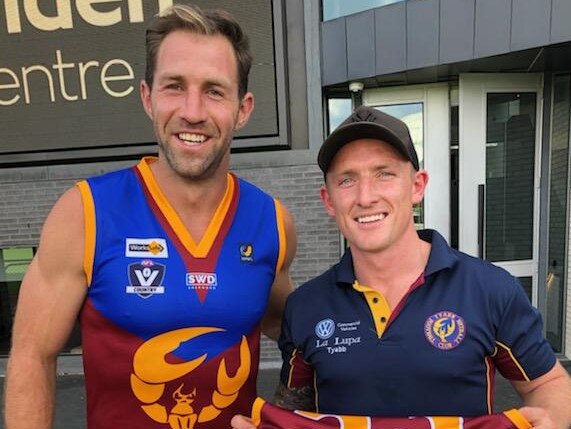 Travis Cloke tries on a Tyabb jumper alongside Yabbies coach Aaron Pacey.