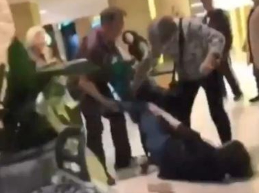 A shopper lies on the ground kicking others during a brawl over baby formula.