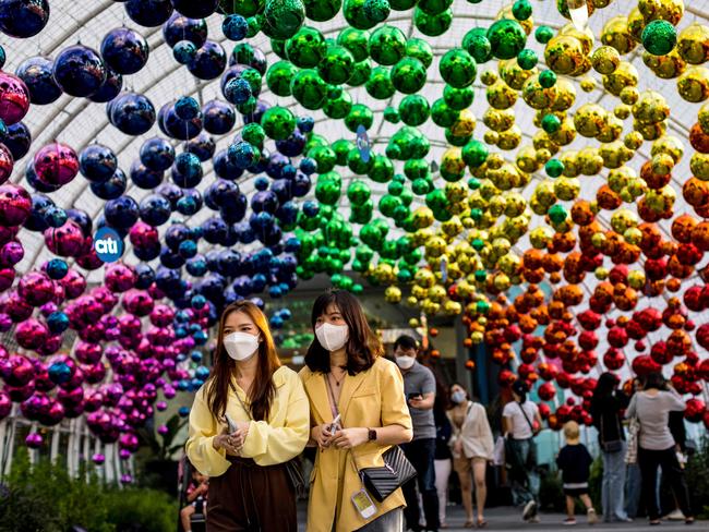 Women wearing face masks walk below decorations outside a shopping mall in Bangkok. Picture: AFP