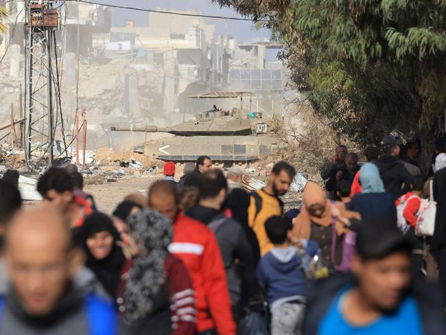 An Israeli armoured vehicle rolls past Palestinians fleeing the fighting in war-torn Gaza on Salaheddine road in the Zeitoun district of the southern part of the Gaza Strip. Picture: AFP