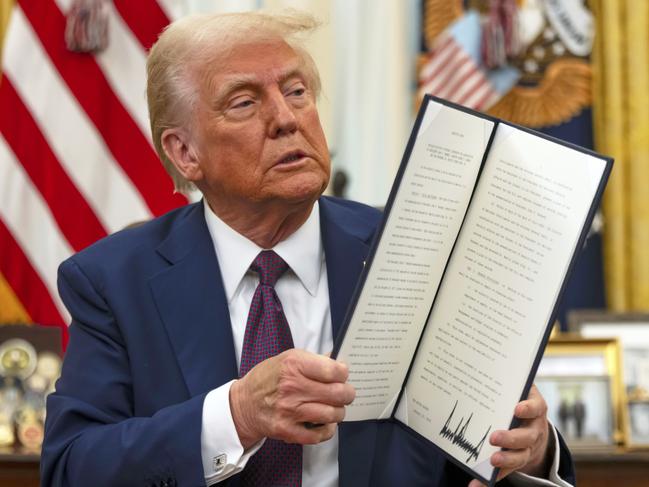 FILE - President Donald Trump holds up a signed executive order aiming to declassify remaining federal records relating to the assassinations of President John F. Kennedy, Sen. Robert F. Kennedy, and Martin Luther King Jr., in the Oval Office of the White House, Jan. 23, 2025, in Washington. (AP Photo/Ben Curtis, File)