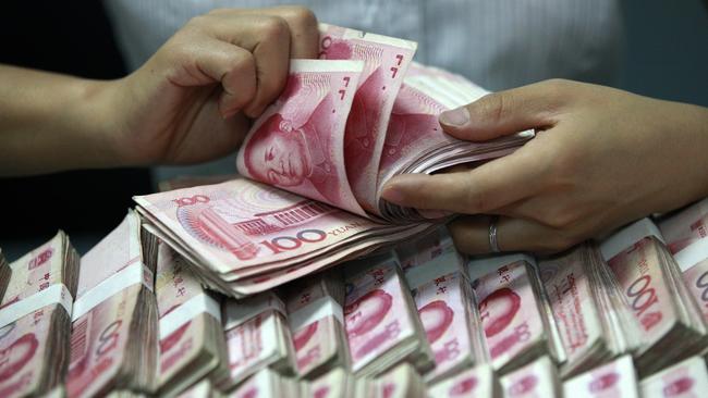 A clerk counts Chinese banknotes at a bank in Huaibe. The lower GDP target comes amid mounting downward pressure in the world’s second-largest economy. Picture: AP