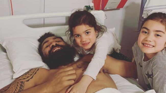 Masoe with his two daughters while flat on his back in hospital.