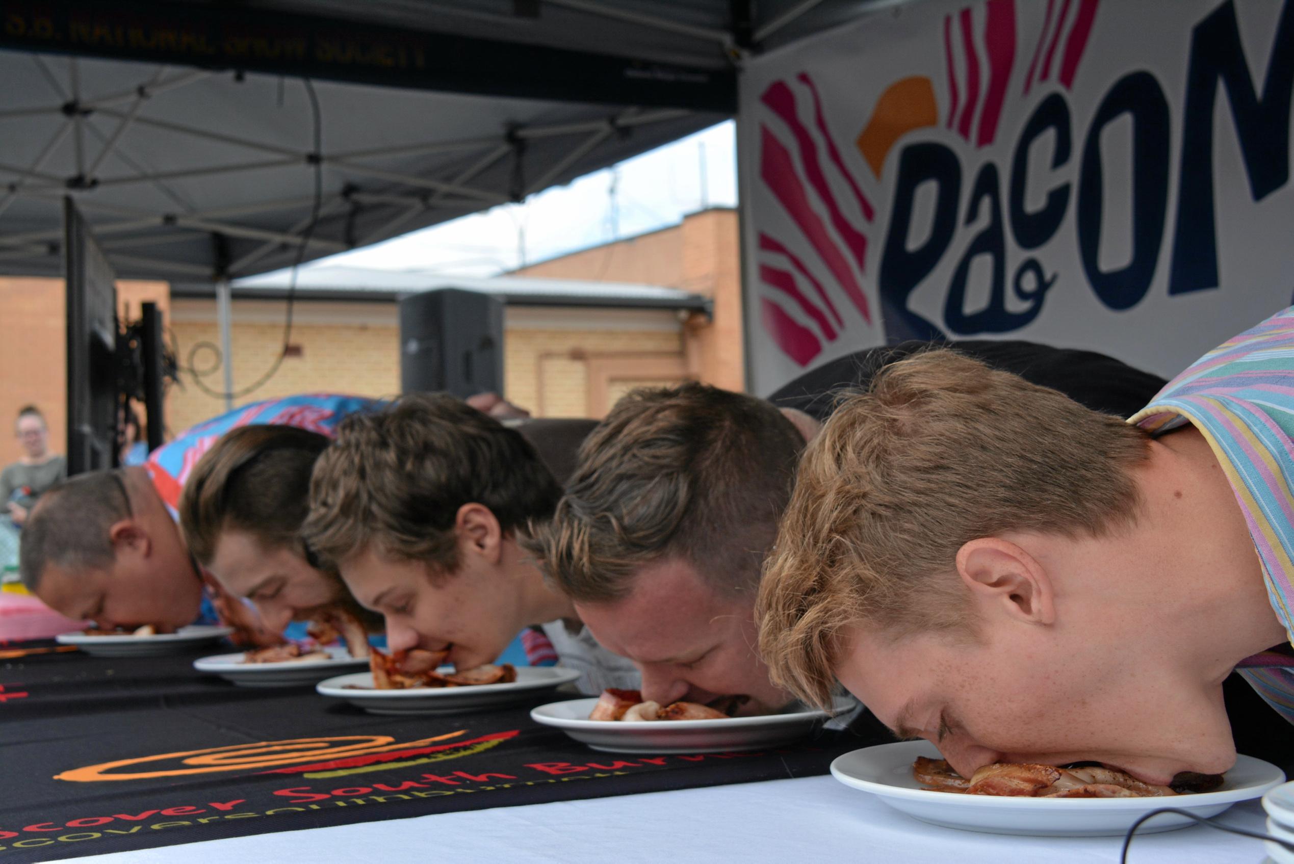 Competitors fight for the top spot at the bacon eating competition during Kingaroy's BaconFest on Saturday August 25. Picture: Jessica McGrath