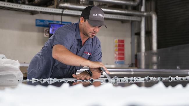 A worker prepares leather for vacuum drying at Packers Leather Tannery at Narangba. Picture Lachie Millard