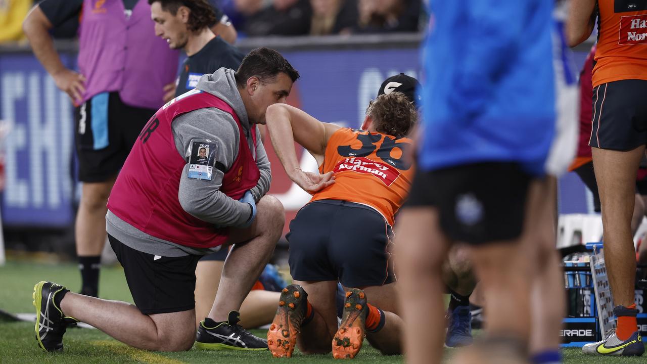 Harry Perryman grabs at his back/ribs after being helped from the field.