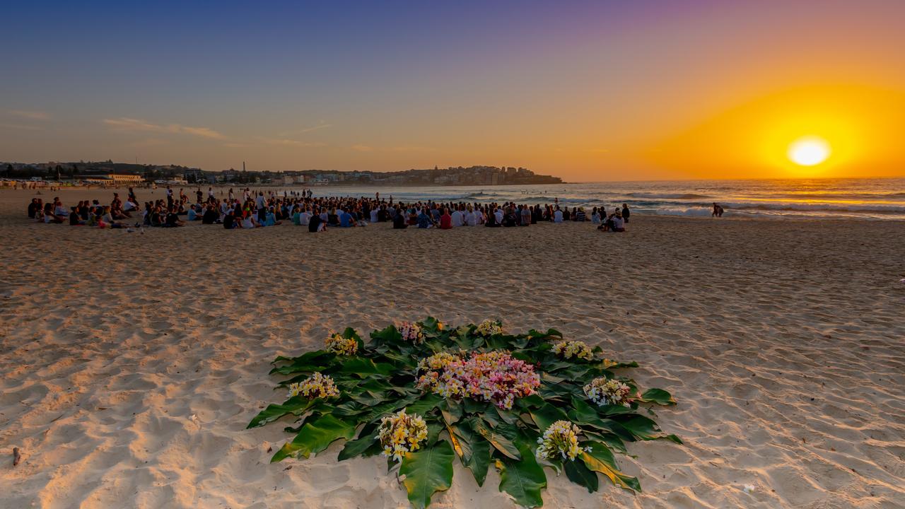 Surfers later headed to the water scattering a frangipani wreath on the ocean. Picture: Monique Harmer