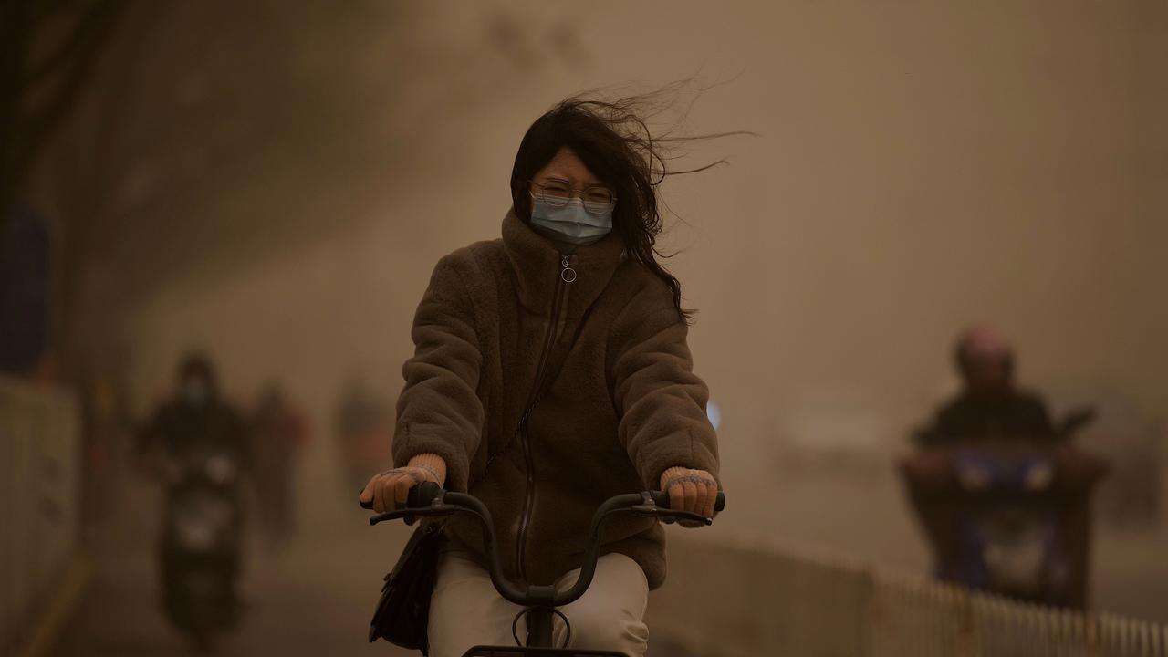 A woman cycles along a street during a sandstorm in Beijing on March 15, 2021. Picture: AFP