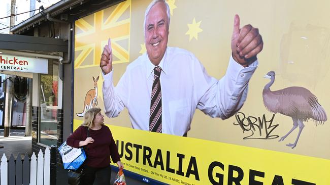 A woman walking past a billboard of United Australia Party leader Clive Palmer in Melbourne.