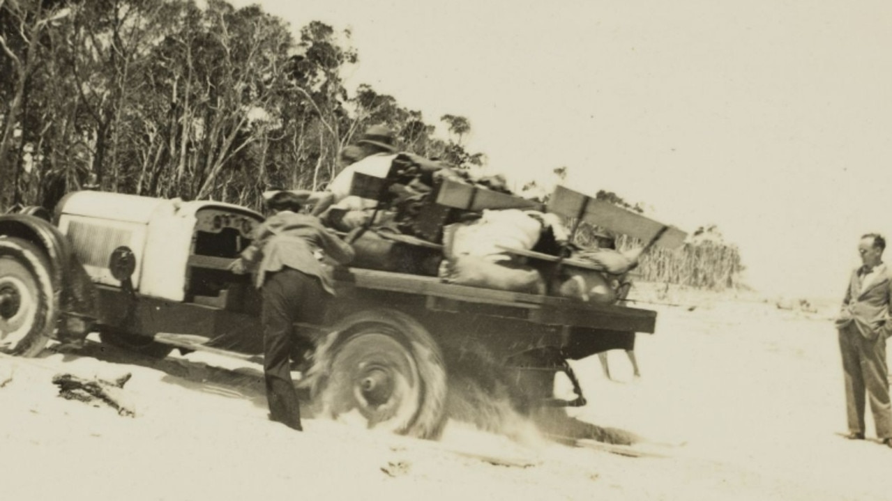 Men pushing a car through soft sand on a beach of North Stradbroke Island Photograph taken during outing over New Years Eve in 1935