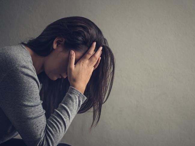 Depressed woman sitting on a chair in dark room at home. Lonly , sad, emotion concept.