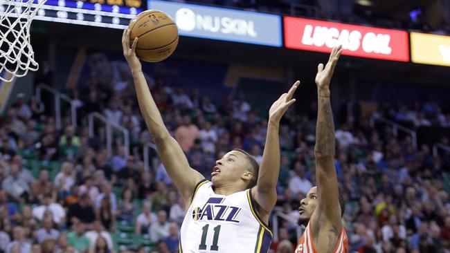 Utah Jazz's Dante Exum (11) lays the ball up as Houston Rockets' Trevor Ariza, right, defends in the first half of an NBA basketball game in Toronto on Wednesday, Oct. 29, 2014. (AP Photo/The Canadian Press, Nathan Denette)