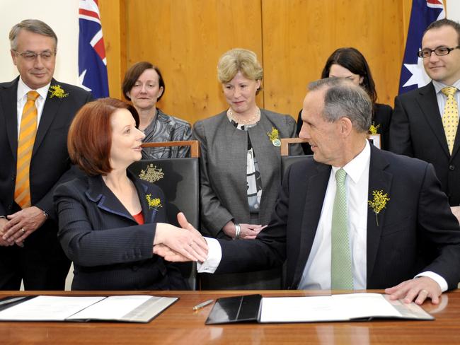 Watched by treasure Wayne Swan (left) and Australian Greens Prime Minister Julia Gillard and Greens leader Bob Brown shake hands after signing a parliamentary agreement in Canberra, Wednesday, Sept. 1, 2010. New Australian Greens MP Adam Bandt (rear, right) has formally sided with Labor in the hopes of forming a minority government. (AAP Image/Alan Porritt) NO ARCHIVING