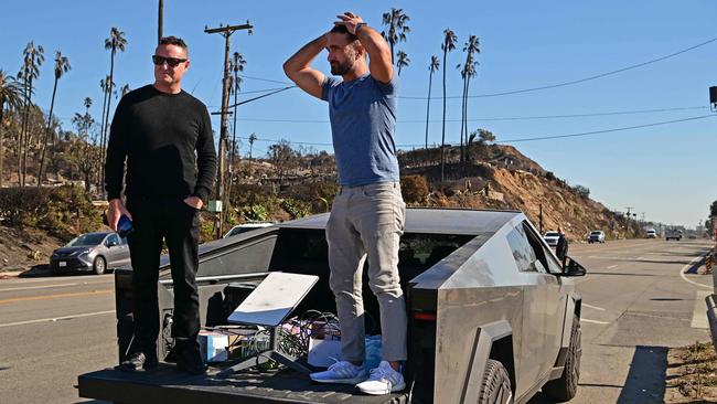 Two mean stand on their Tesla Cybertruck, with a Starlink dish, as they wait for police to escort them, along the Pacific Coast Highway, near the Pacific Palisades neighbourhood. Picture: AFP