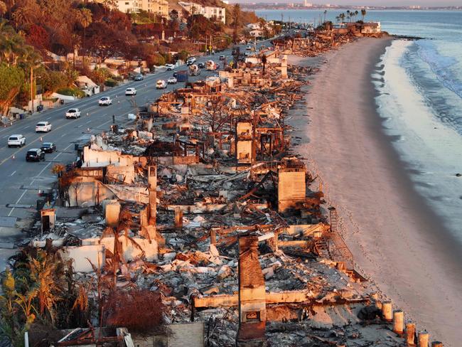 MALIBU, CALIFORNIA - JANUARY 15: An aerial view of repair vehicles at sunset passing near beachfront homes that burned in the Palisades Fire as wildfires cause damage and loss through the LA region on January 15, 2025 in Malibu, California. Multiple wildfires fueled by intense Santa Ana Winds are still burning across Los Angeles County, with at least 25 dead, more than 12,000 structures destroyed or damaged, and 40,000 acres burned. More than 88,000 people remain under evacuation orders as high winds are forecast.   Mario Tama/Getty Images/AFP (Photo by MARIO TAMA / GETTY IMAGES NORTH AMERICA / Getty Images via AFP)