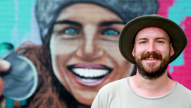 Artist Shannon Boyd poses for photographs with his mural of Jess Fox in Penrith.