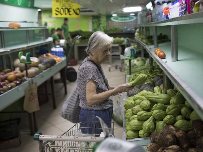 A woman shops surrounded by partially empty shelves in a market in Rio de Janeiro, Brazil. Picture: Leo Correa