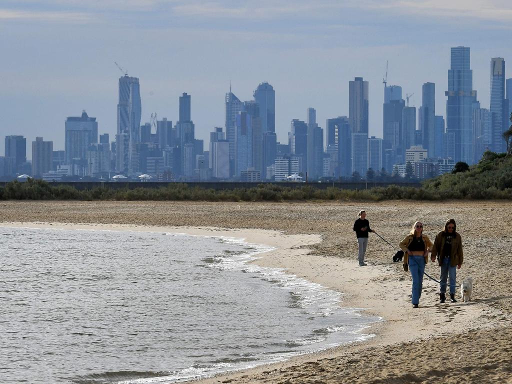 People enjoy a mid-winter walk on Brighton Beach in Melbourne yesterday as the city's latest Covid-19 outbreak recedes while Sydney battles a fresh cluster. Picture: William West AFP)