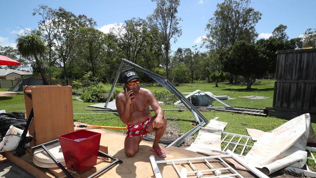 Helensvale resident Ime King in the remains of his shed, struggling to call for help amid phone service outages. Picture Glenn Hampson