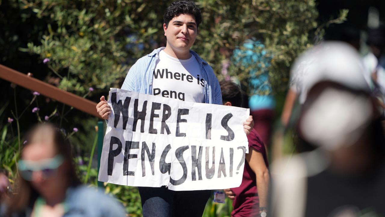 A protester holding a sign and wearing a T-shirt reading "where is Peng Shuai"