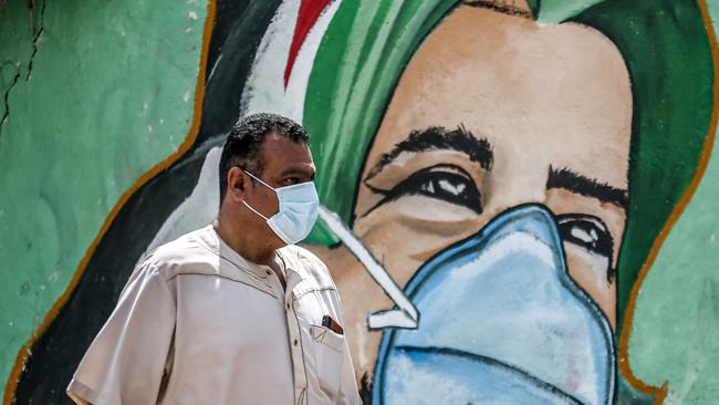 A mask-clad man walks past a mural on a wall in Rafah in the southern Gaza Strip. Picture: AFP