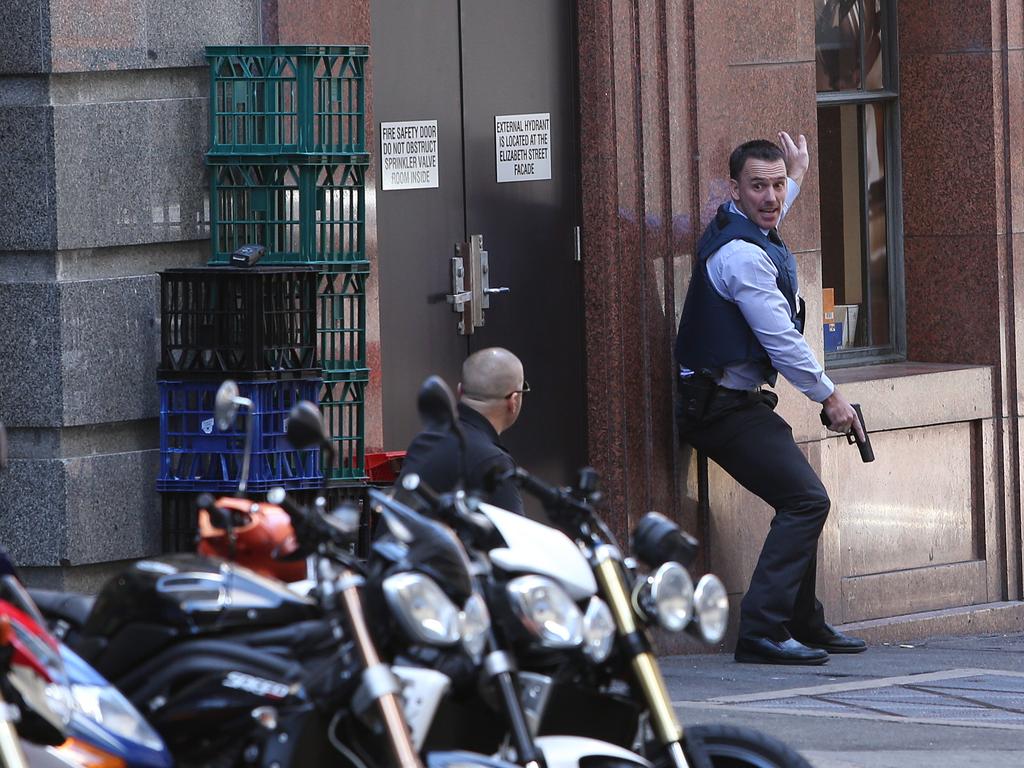 2. An armed police officer signals instructions to a colleague minutes after the cafe manager Tori Johnson called Triple 000 with a gun pointed to his head by an unknown customer. Picture: Richard Dobson