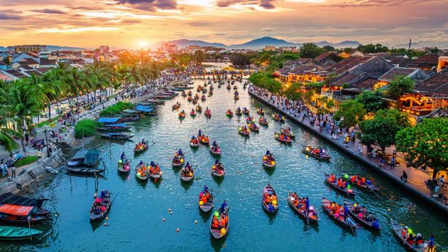Boats light up Hoi An's Thu Bon River at twilight.