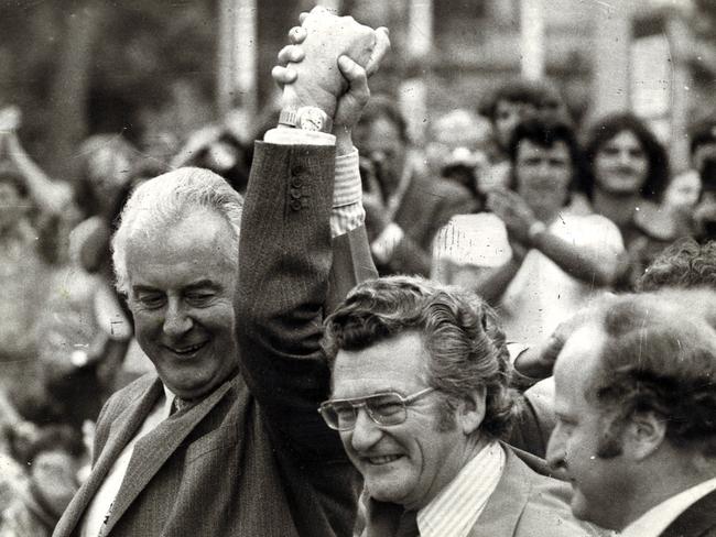 Gough Whitlam and Bob Hawke clasp hands in salute at ALP rally in 1975.