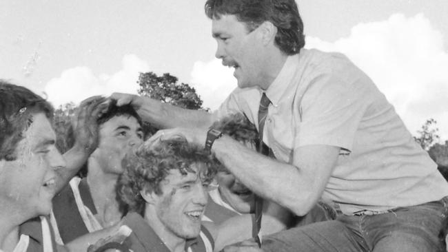 Football premiership winners jubiliant Clarence players hoist coach Robbie Shaw (Rob, Robert) in the air after the final siren in the 1984 grand final.