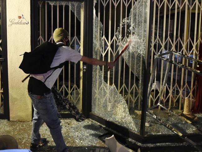 A man smashes the front window of the Realm of the Goddess jewellery store on Melrose Avenue in Los Angeles. Picture: AP