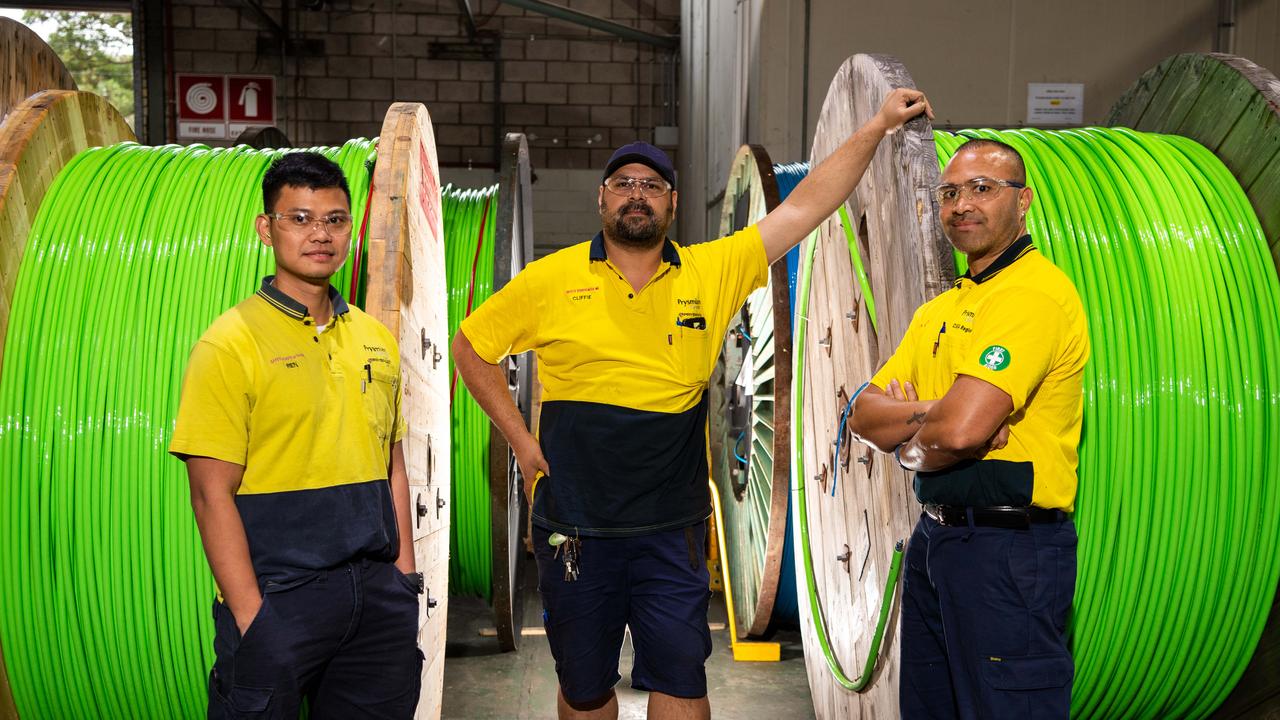 Workers pose with spools of fibre optic cables at a northern Sydney factory supplying the NBN. Unless these cables come all the way to your door you can’t get the faster new plans. Picture: AAP Image / Monique Harmer