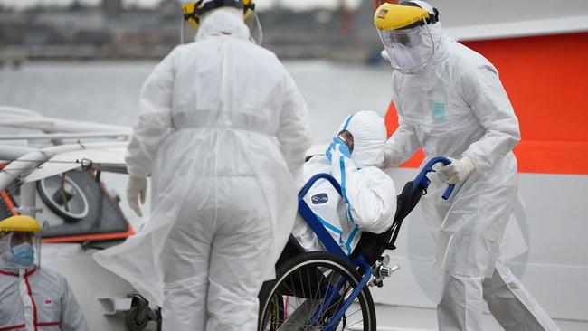 Medical workers transfer a sick passenger with COVID-19 from the Greg Mortimer cruise liner to an ambulance at Montevideo's on April 8. Picture: Daniel Rodriguez/ad hoc/AFP