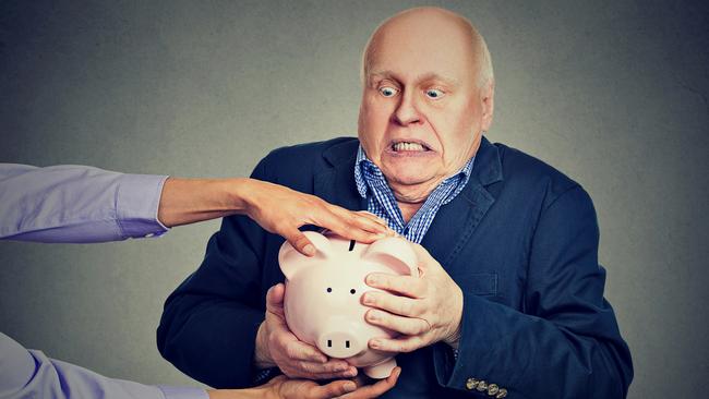 Elderly upset scared business man holding piggy bank trying to protect his savings from being stolen isolated gray background; greed generic senior money