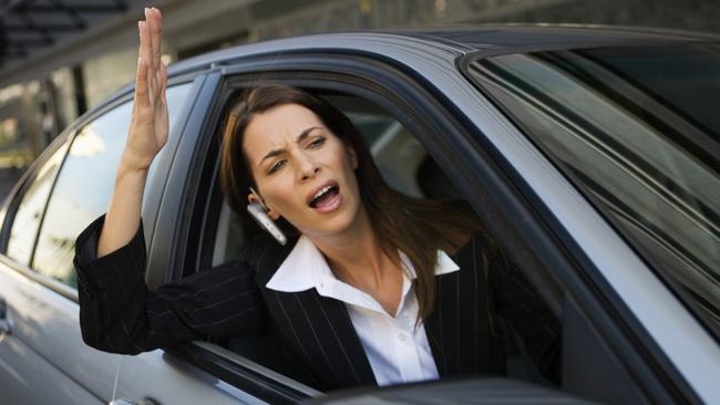 Businesswoman yelling out of car window. Road rage. Generic image.