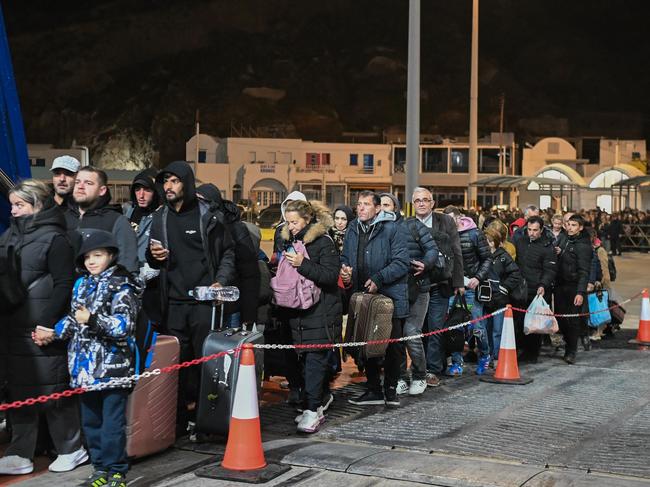 People embark a ferry as they leave in the wake of recurring earthquakes, on the Greek Island of Santorini, on February 4, 2025. Fresh overnight tremors shook Greece's top tourist island Santorini, media reports said, prompting people to sleep outdoors and others to leave by plane or ferry. (Photo by -STR / AFP)