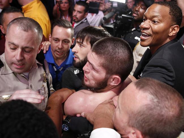 Khabib Nurmagomedov, bottom center, is held back outside of the cage after fighting Conor McGregor in a lightweight title mixed martial arts bout at UFC 229 in Las Vegas, Saturday, Oct. 6, 2018. Nurmagomedov won the fight by submission during the fourth round to retain the title. (AP Photo/John Locher)