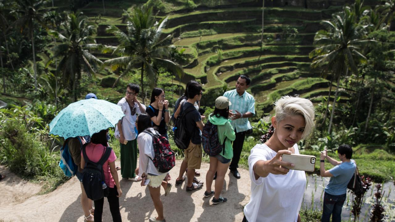 A tourist takes a selfie before a background of the scenic Tegalalang rice terrace in Gianyar, Bali. Picture: Agung Parameswara/Getty Images