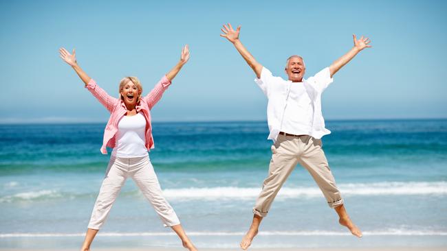 Full length of senior couple jumping in joy on beach