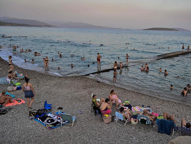 People cool off in the sea during sunset on a beach at Ancient Asini as Greece is hit by a heatwave. Picture: Louisa Gouliamaki/AFP